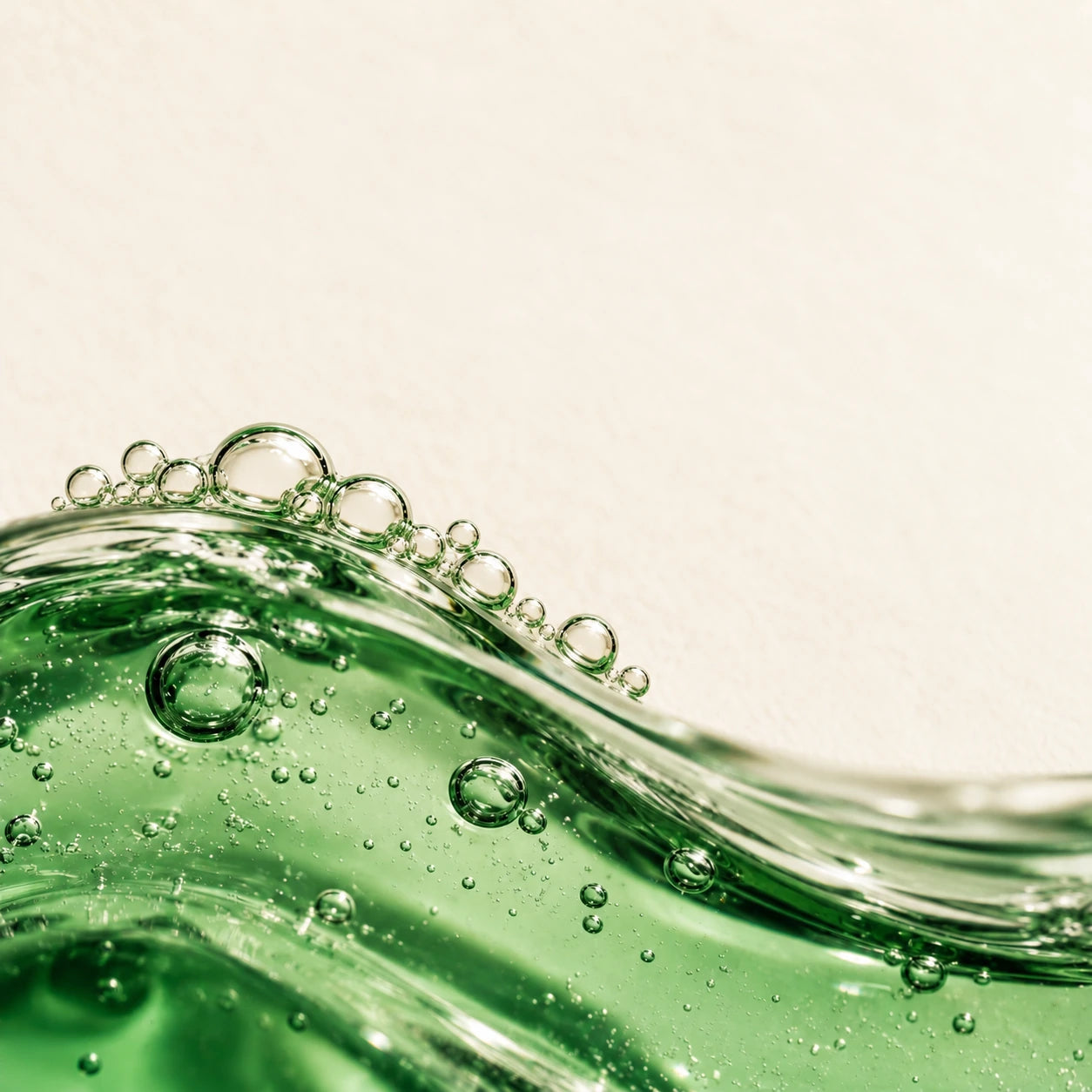 Transparentes grünes Gel mit feinen Luftbläschen vor warmem Cremeweiß