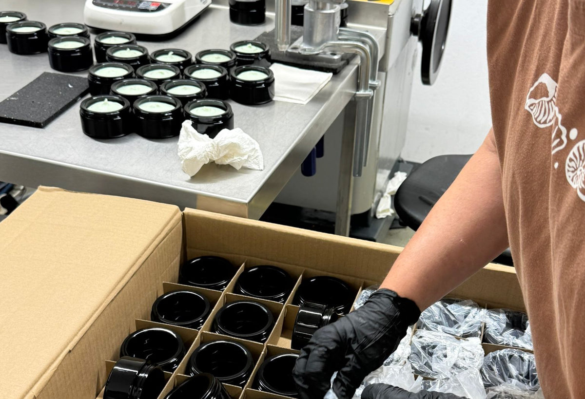 Einblick in die Kapua Produktion: Cremetiegel am Abfülltisch und Violettglas in der Vorbereitung