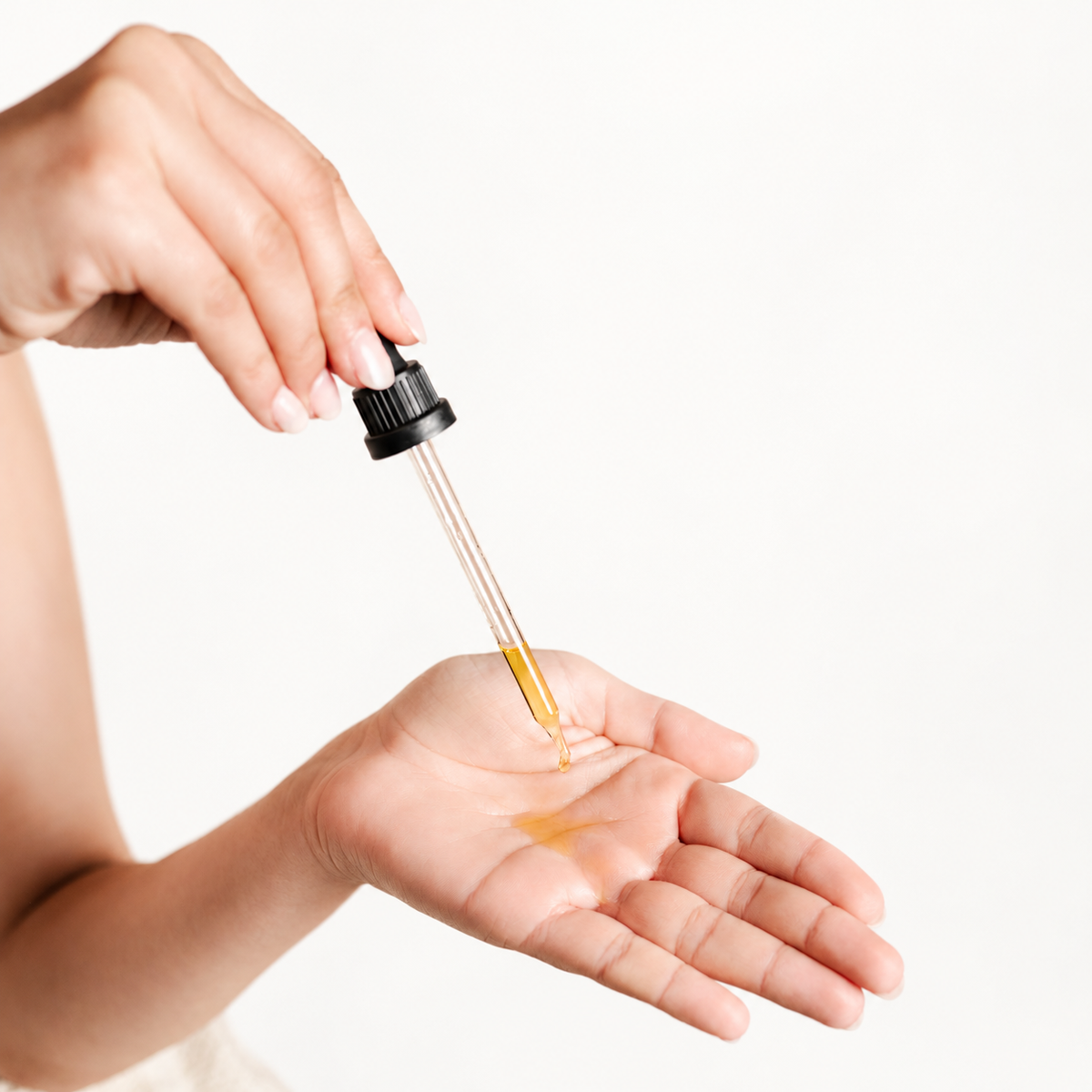 Ein Tropfen Körperöl wird mit einer Pipette in die Hand gegeben