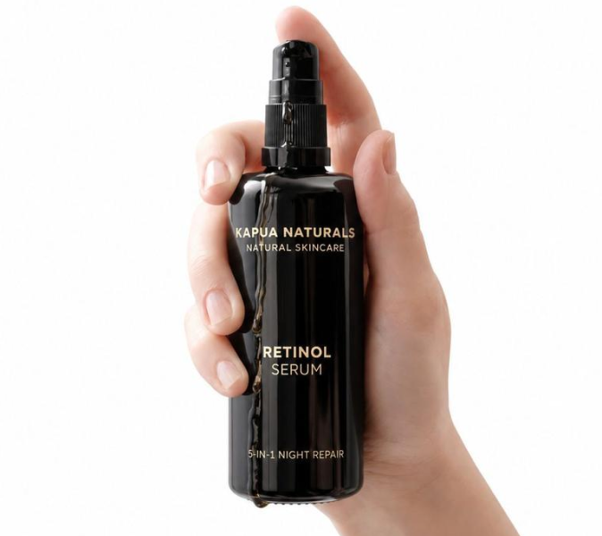 Eine Hand hält das aktuelle Kapua Retinol Serum vor weißem Hintergrund