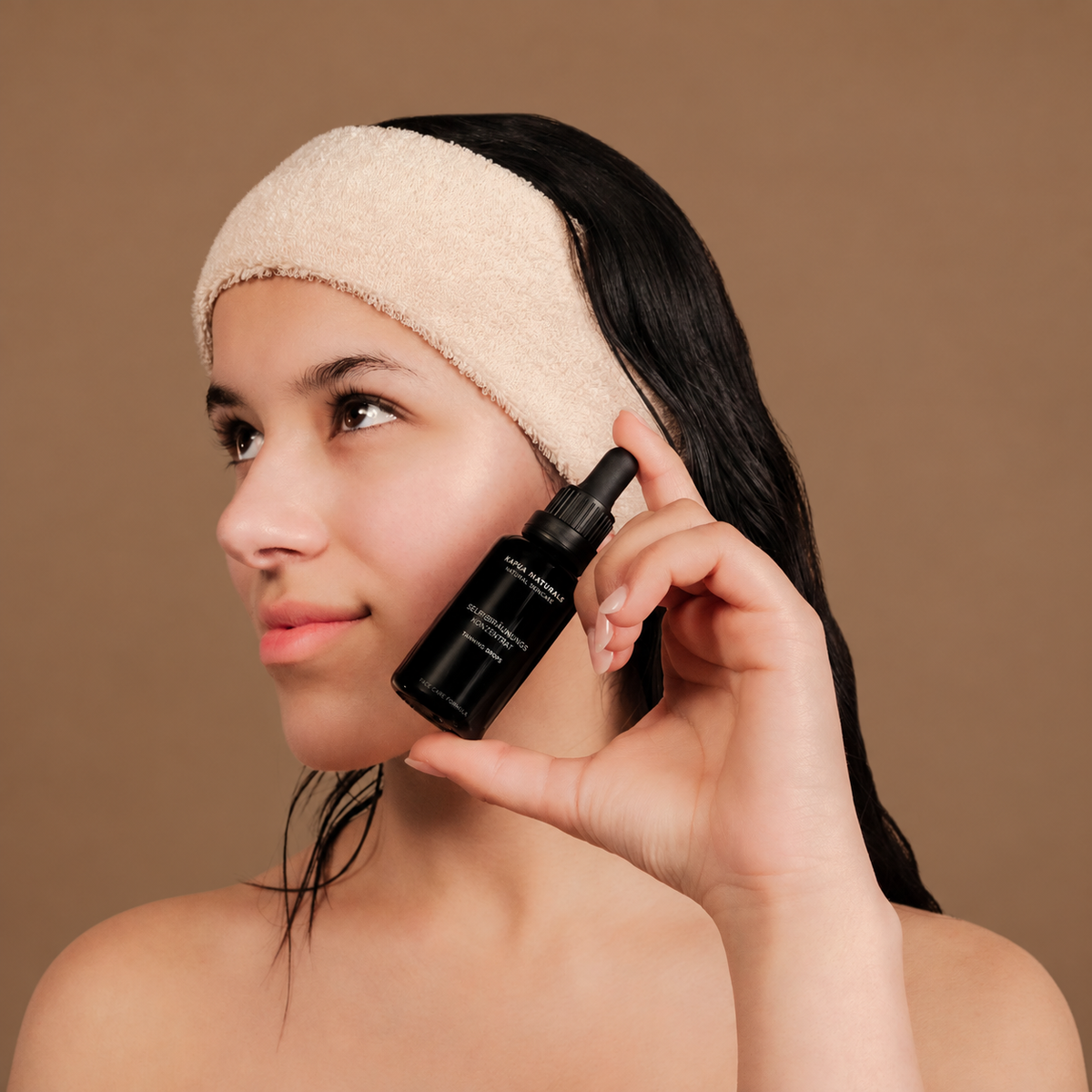 Model mit Kapua Naturals Tanning Drops vor warmbraunem Hintergrund in der Produktfarbe