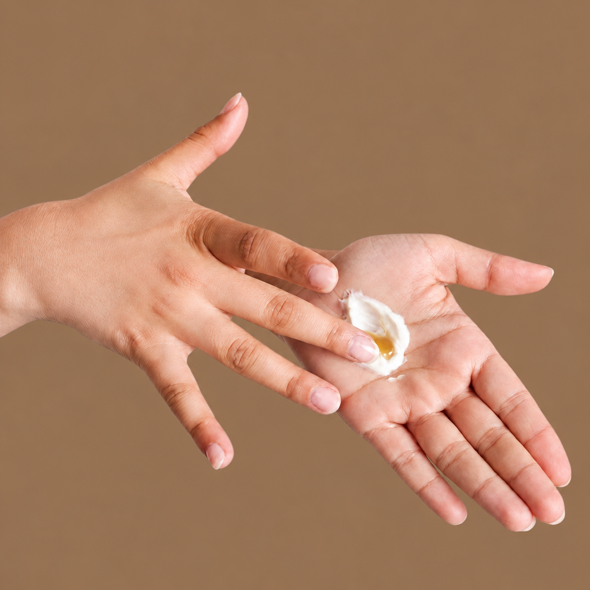 Tanning Drops mit Creme in der Hand mischen – Anwendung vor warmbraunem Hintergrund